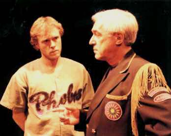 A young actor dressed for sport looks at an older military man.